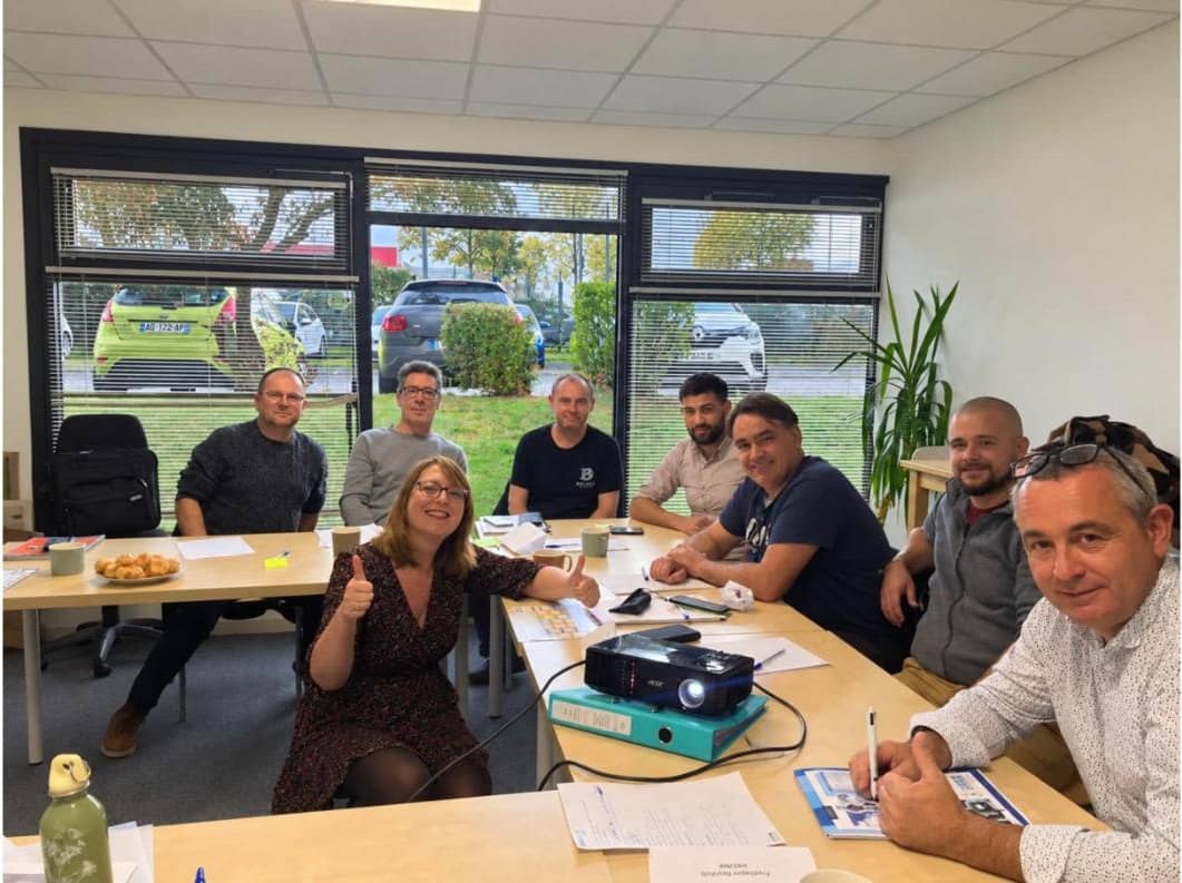 Nathalie Chiffoleau, pouces levés, au milieu d’un groupe en formation autour d’une table